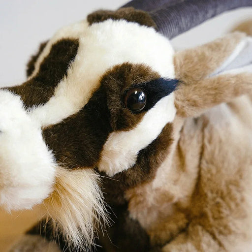 Close-up of a plush goat with brown, black, and white fur.