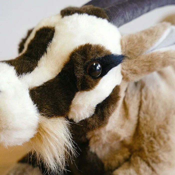 Close-up of a plush goat with brown, black, and white fur.