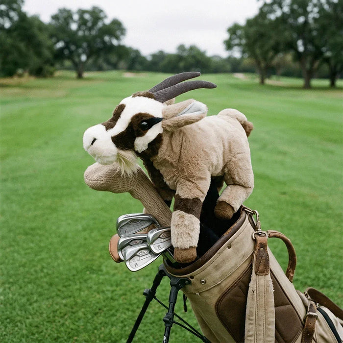 Plush goat headcover on a golf club headcover with a golf bag in the background on a golf course.