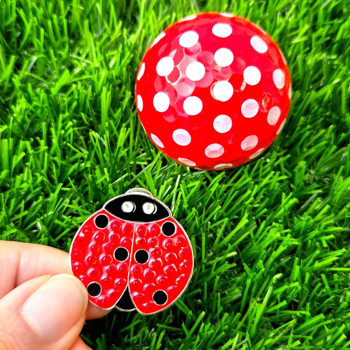 A red ladybug-shaped ball marker with black spots and crystals