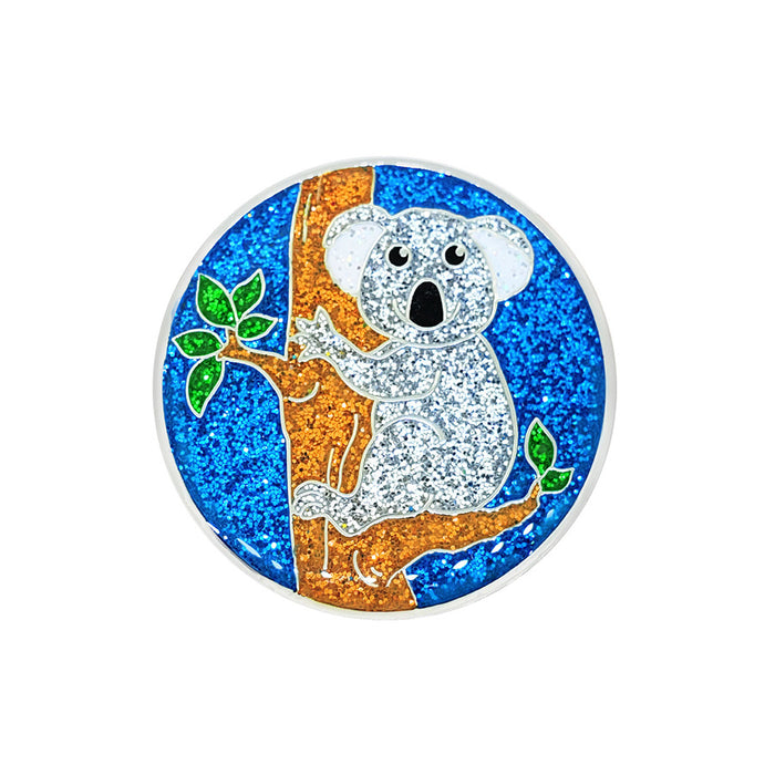 Glittery round object with a koala on a tree branch against a blue background