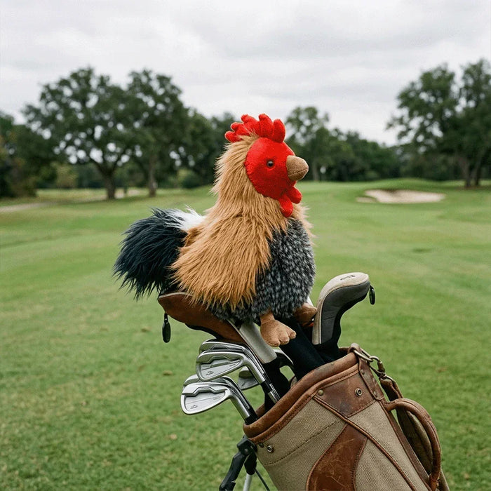 Plush rooster headcover on top of a golf bag with clubs on a golf course.