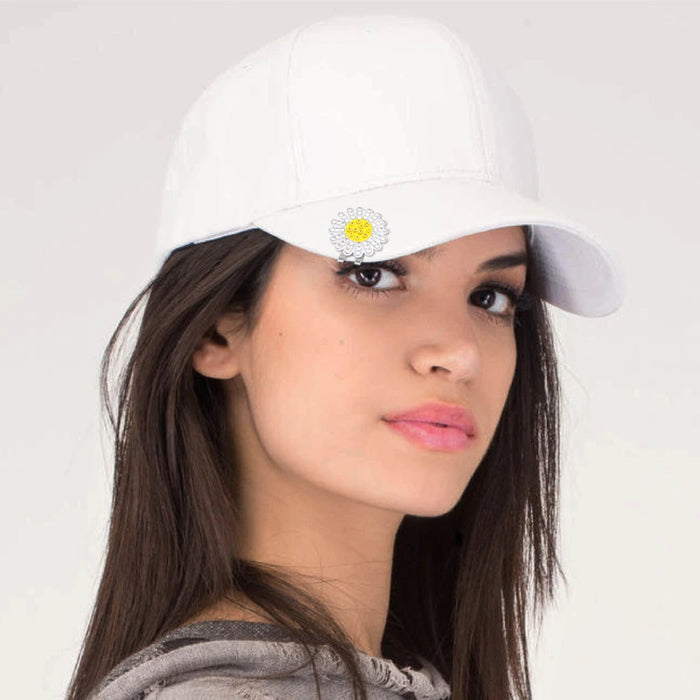 Woman wearing a white cap with a sun flower design ball marker hat clip on a white background