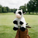 Plush cow headcover in a golf bag on a golf course